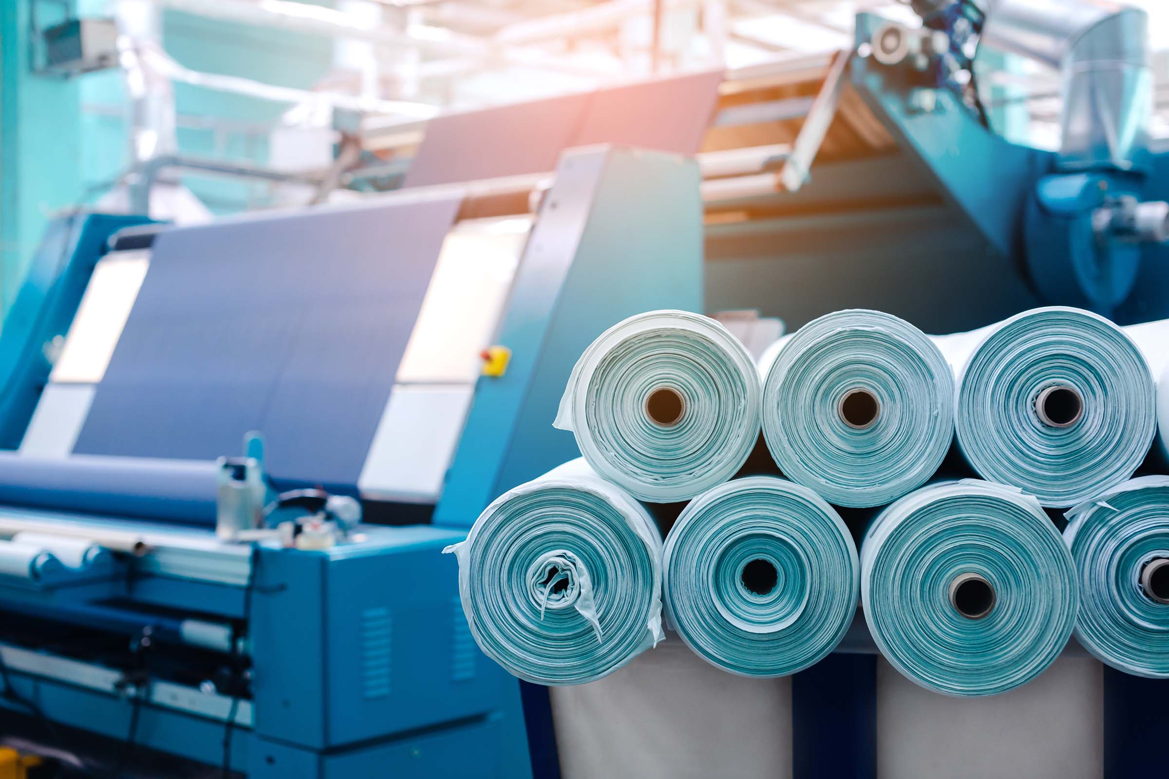 Eine Produktionsmaschine für Spannbetttücher mit vielen Rollen unverarbeitetem Material